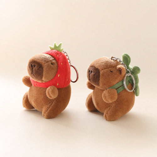 Two capybara plush bag charms: strawberry hat and turtle backpack